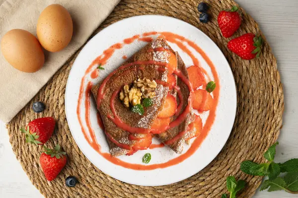 Çilek ve meyve sosuyla dolu çikolatalı krepler. Noel süslemeleri ile en üstteki görünüm masası.