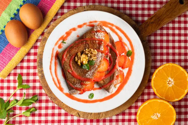 Çilek ve meyve sosuyla dolu çikolatalı krepler. Noel süslemeleri ile en üstteki görünüm masası.