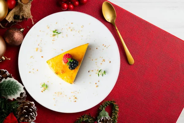 Bisküvi tabanlı yanmış Katalan kremalı tartı. Noel süslemeleri olan bir masanın üst görünümü.