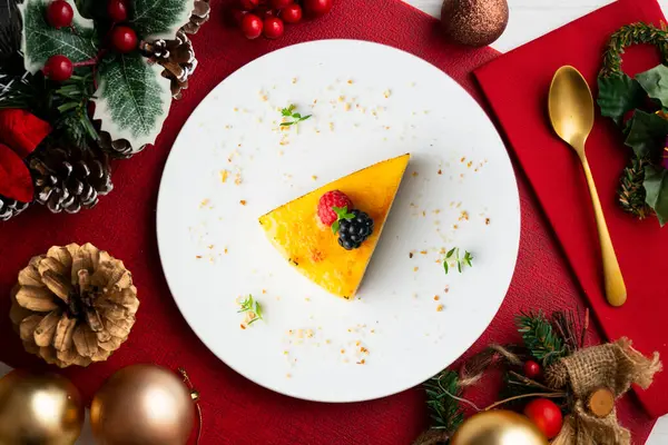 Bisküvi tabanlı yanmış Katalan kremalı tartı. Noel süslemeleri olan bir masanın üst görünümü.
