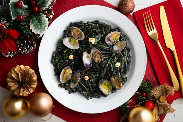 İspanyol siyah Fideua 'sı. Geleneksel erişte tarifi, midye ve sarımsak yağı. Noel süslemeleri ile en üstteki görünüm masası.