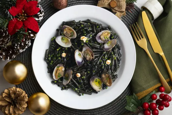 İspanyol siyah Fideua 'sı. Geleneksel erişte tarifi, midye ve sarımsak yağı. Noel süslemeleri ile en üstteki görünüm masası.