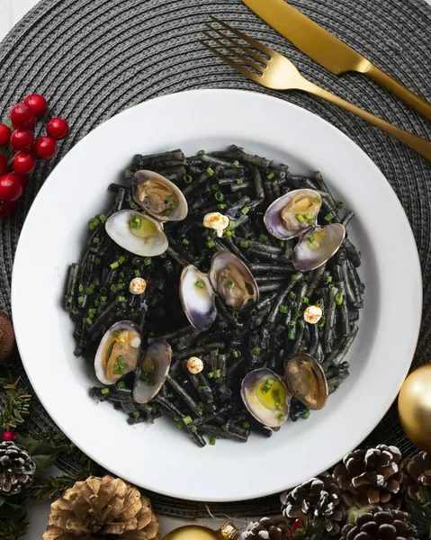 İspanyol siyah Fideua 'sı. Geleneksel erişte tarifi, midye ve sarımsak yağı. Noel süslemeleri ile en üstteki görünüm masası.