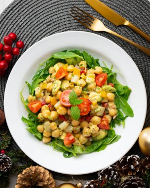 Avokado ve sebzeli Akdeniz nohut salatası. Noel süslemeleri ile en üstteki görünüm masası.