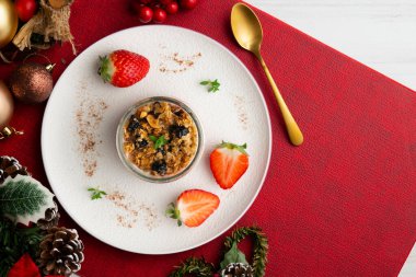 Çilekli Yunan yoğurdu ve tahıl gevreği ve fındıklı granola. Noel süslemeleri ile en üstteki görünüm masası.