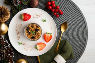 Çilekli Yunan yoğurdu ve tahıl gevreği ve fındıklı granola. Noel süslemeleri ile en üstteki görünüm masası.