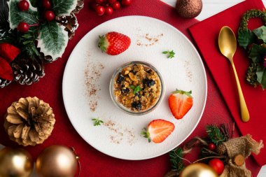 Çilekli Yunan yoğurdu ve tahıl gevreği ve fındıklı granola. Noel süslemeleri ile en üstteki görünüm masası.