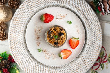 Çilekli Yunan yoğurdu ve tahıl gevreği ve fındıklı granola. Noel süslemeleri ile en üstteki görünüm masası.