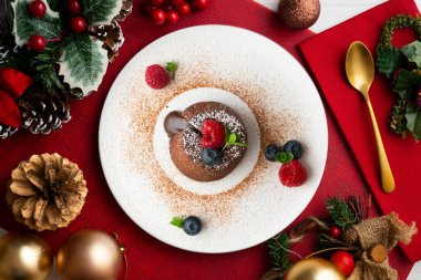 Çok güzel bir çikolatalı lav keki Noel süslemeleri ile birlikte en üstten görülebilir..