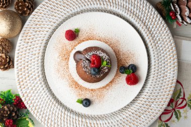 Çok güzel bir çikolatalı lav keki Noel süslemeleri ile birlikte en üstten görülebilir..