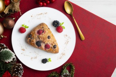 Böğürtlen, ahududu ve çikolata parçacıklı üçgen İngiliz çörekleri. Noel süslemeleri ile en üstteki görünüm masası.