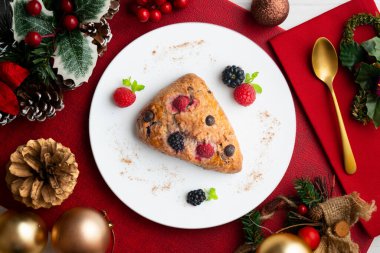 Böğürtlen, ahududu ve çikolata parçacıklı üçgen İngiliz çörekleri. Noel süslemeleri ile en üstteki görünüm masası.
