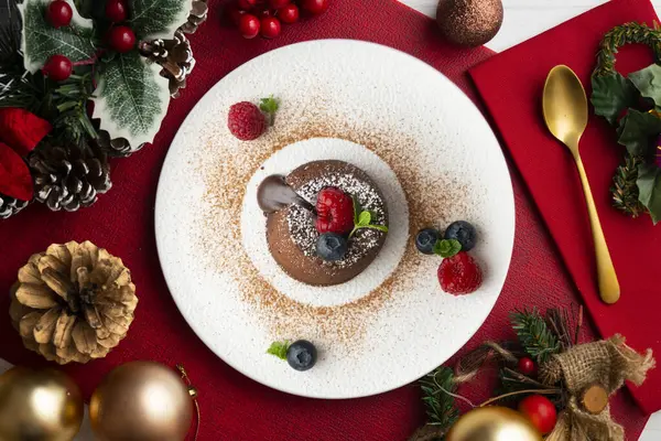 Çok güzel bir çikolatalı lav keki Noel süslemeleri ile birlikte en üstten görülebilir..