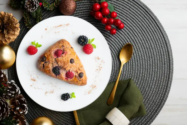 Böğürtlen, ahududu ve çikolata parçacıklı üçgen İngiliz çörekleri. Noel süslemeleri ile en üstteki görünüm masası.
