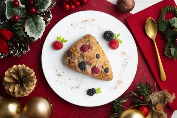 Böğürtlen, ahududu ve çikolata parçacıklı üçgen İngiliz çörekleri. Noel süslemeleri ile en üstteki görünüm masası.