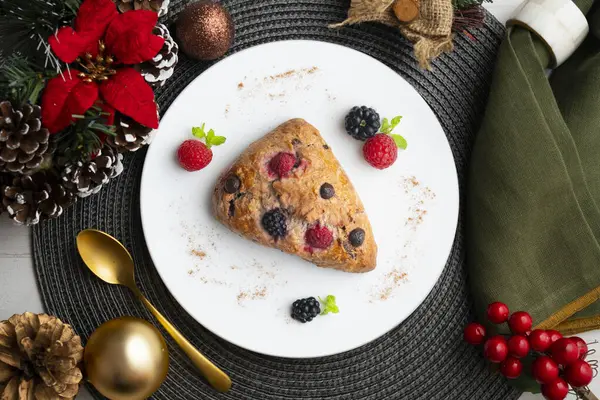 Böğürtlen, ahududu ve çikolata parçacıklı üçgen İngiliz çörekleri. Noel süslemeleri ile en üstteki görünüm masası.