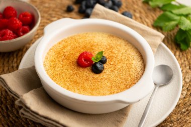 Zencefil aromalı yumurta kreması ve tarçın ve kırmızı böğürtlenlerle süslenmiş..