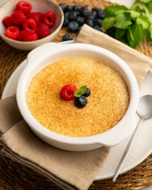 Zencefil aromalı yumurta kreması ve tarçın ve kırmızı böğürtlenlerle süslenmiş..