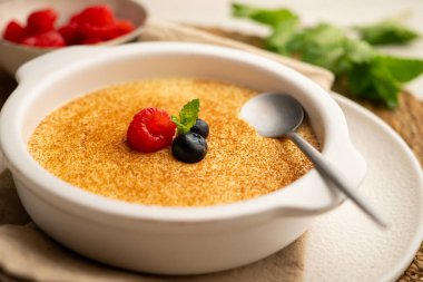 Zencefil aromalı yumurta kreması ve tarçın ve kırmızı böğürtlenlerle süslenmiş..