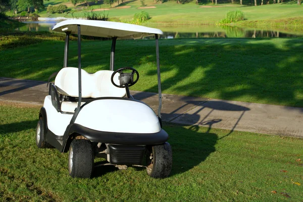 White golf cart parked on the golf course with morning sunlight