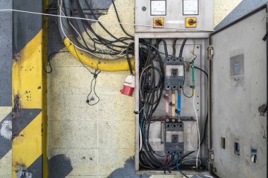 Tehlikeli üç aşamalı 220 V elektrik kesici çelik dolap. Kablolar düzgün değil, güç bağlantı kutusu harici beton duvara bağlı..