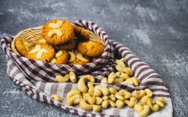 Tahta sepetin üzerinde kaju fıstıklı kurabiyeler, önünde kaju fıstığı serpiştirilmiş bez parçasıyla tabağı süsleyin, ketojenik diyet.