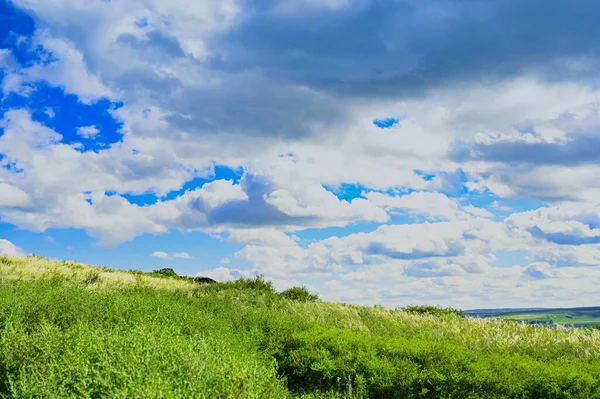 Yeşil doğal bir manzara üzerinde yaz nehri, gökyüzü, dağlar ve bulutlar.