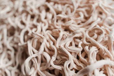 Tangled beige threads yarn noodles texture background