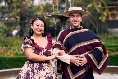 Şilili huasolar gibi giyinmiş, geleneksel bir Şili dansı olan cueca dansı için romantik poz veren genç bir çiftin portresi. Şili gelenekleri, kutlamalar ve kültür.