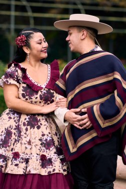 Şilili huasolar gibi giyinmiş, geleneksel bir Şili dansı olan cueca dansı için romantik poz veren genç bir çiftin portresi. Şili gelenekleri, kutlamalar ve kültür.