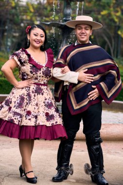 Şilili huasolar gibi giyinmiş, geleneksel bir Şili dansı olan cueca dansı için romantik poz veren genç bir çiftin portresi. Şili gelenekleri, kutlamalar ve kültür.