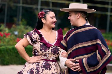 Şilili huasolar gibi giyinmiş, geleneksel bir Şili dansı olan cueca dansı için romantik poz veren genç bir çiftin portresi. Şili gelenekleri, kutlamalar ve kültür.