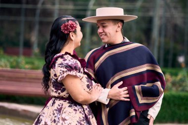 Şilili huasolar gibi giyinmiş, geleneksel bir Şili dansı olan cueca dansı için romantik poz veren genç bir çiftin portresi. Şili gelenekleri, kutlamalar ve kültür.
