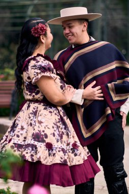 Şilili huasolar gibi giyinmiş, geleneksel bir Şili dansı olan cueca dansı için romantik poz veren genç bir çiftin portresi. Şili gelenekleri, kutlamalar ve kültür.