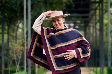 Şilili bir huaso gibi giyinmiş gülümseyen, neşeli bir gencin portresi geleneksel bir Şili dansı olan cueca dansını kutluyor ve poz veriyor. Şili gelenekleri, kutlamalar ve kültür.                           