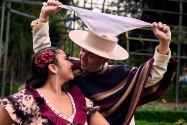 Şilili huasolar gibi giyinmiş, romantik poz veren ve geleneksel bir Şili dansı olan Cueca 'yı öpüp dans eden genç bir çiftin portresi. Şili gelenekleri, kutlamalar ve kültür.                          