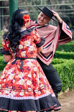 Şilili huasolar gibi giyinmiş, birbirlerine bakıp geleneksel bir Şili dansı olan cueca dansı için romantik poz veren genç bir çiftin portresi. Şili gelenekleri, kutlamalar ve kültür.