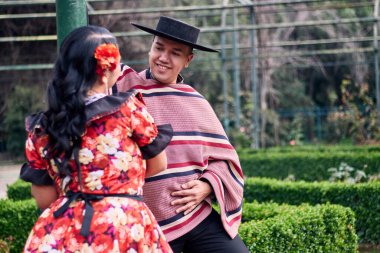 Şilili huasolar gibi giyinmiş, birbirlerine bakıp geleneksel bir Şili dansı olan cueca dansı için romantik poz veren genç bir çiftin portresi. Şili gelenekleri, kutlamalar ve kültür.