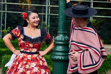 Şilili huasolar gibi giyinmiş, birbirlerine bakıp geleneksel bir Şili dansı olan cueca dansı için romantik poz veren genç bir çiftin portresi. Şili gelenekleri, kutlamalar ve kültür.