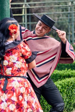 Şilili huasolar gibi giyinmiş, birbirlerine bakıp geleneksel bir Şili dansı olan cueca dansı için romantik poz veren genç bir çiftin portresi. Şili gelenekleri, kutlamalar ve kültür.