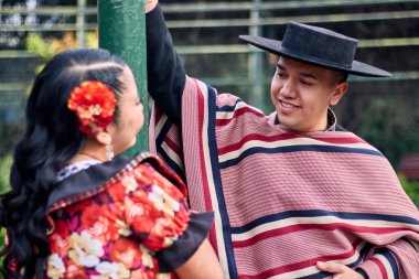 Şilili huasolar gibi giyinmiş, birbirlerine bakıp geleneksel bir Şili dansı olan cueca dansı için romantik poz veren genç bir çiftin portresi. Şili gelenekleri, kutlamalar ve kültür.