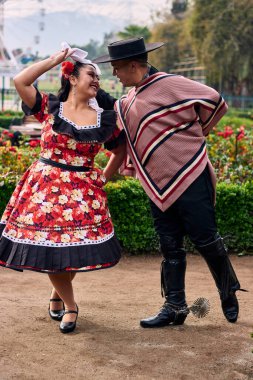 Şilili huasolar gibi giyinmiş, birbirlerine bakıp geleneksel bir Şili dansı olan cueca dansı için romantik poz veren genç bir çiftin portresi. Şili gelenekleri, kutlamalar ve kültür.