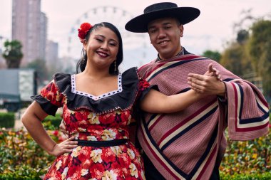 Şilili huasolar gibi giyinmiş, birbirlerine bakıp geleneksel bir Şili dansı olan cueca dansı için romantik poz veren genç bir çiftin portresi. Şili gelenekleri, kutlamalar ve kültür.
