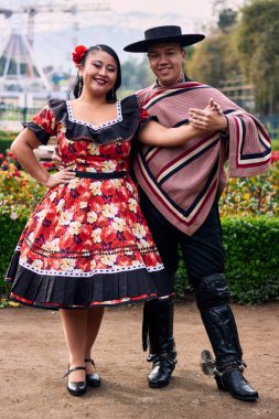 Şilili huasolar gibi giyinmiş, birbirlerine bakıp geleneksel bir Şili dansı olan cueca dansı için romantik poz veren genç bir çiftin portresi. Şili gelenekleri, kutlamalar ve kültür.