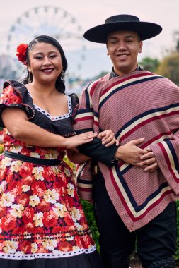 Şilili huasolar gibi giyinmiş, birbirlerine bakıp geleneksel bir Şili dansı olan cueca dansı için romantik poz veren genç bir çiftin portresi. Şili gelenekleri, kutlamalar ve kültür.