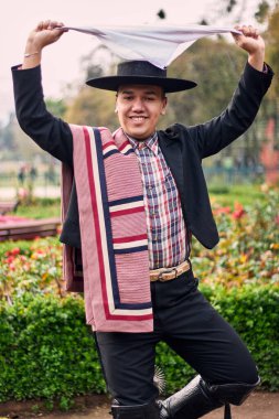 Şilili bir huaso gibi giyinmiş gülümseyen, neşeli bir gencin portresi geleneksel bir Şili dansı olan cueca dansını kutluyor ve poz veriyor. Şili gelenekleri, kutlamalar ve kültür.