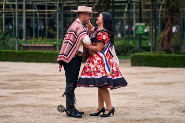 Şilili genç bir Latin çift, Şilili huasolar gibi giyinmiş, çok romantik ve neşeli, el ele tutuşuyorlar, geleneksel bir Şili dansı olan cueca 'yı öpüp dans etmek üzereler. Şili Bağımsızlık Günü kutlamaları.