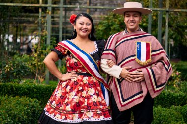 Şilili huasolar gibi giyinmiş, geleneksel bir Şili dansı olan cueca dansı için romantik ve neşeyle poz veren genç bir çiftin portresi. Şili gelenekleri, kutlamalar ve kültür.