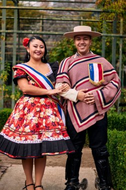 Şilili huasolar gibi giyinmiş, geleneksel bir Şili dansı olan cueca dansı için romantik ve neşeyle poz veren genç bir çiftin portresi. Şili gelenekleri, kutlamalar ve kültür.
