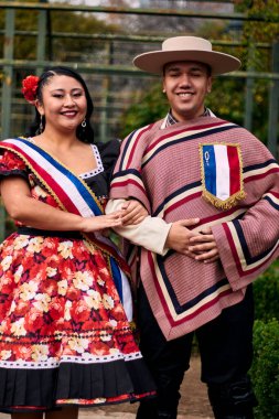 Şilili huasolar gibi giyinmiş, geleneksel bir Şili dansı olan cueca dansı için romantik ve neşeyle poz veren genç bir çiftin portresi. Şili gelenekleri, kutlamalar ve kültür.